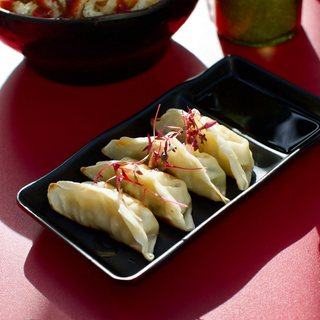 Four pan-fried gyoza on a black plate