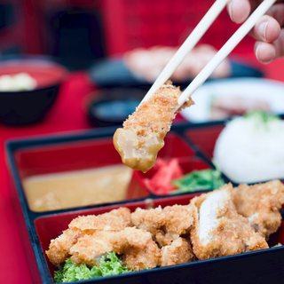 Panko-crumbed katsu being lifted through curry sauce