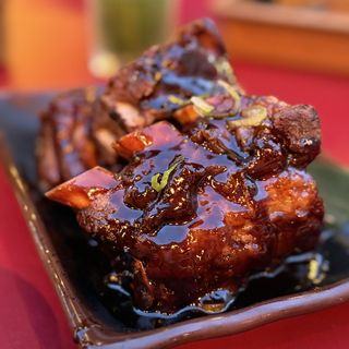 Sticky soy pork glazed and glossy on a black dish